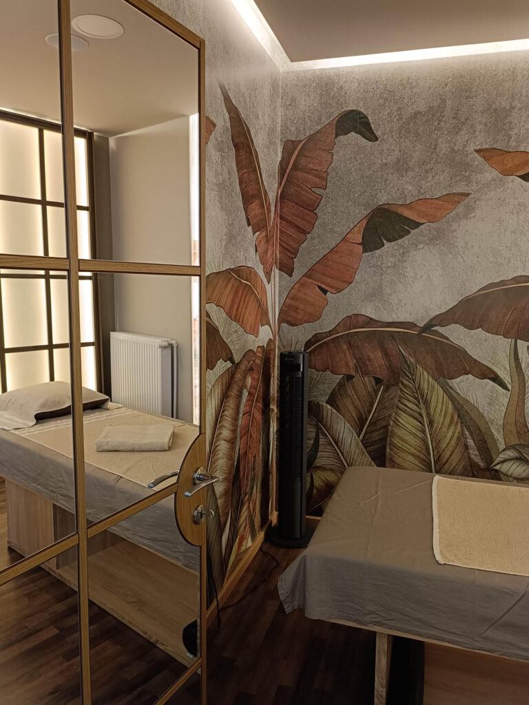 Φωτογραφία όπου φαίνεται η ταπετσαρία με τα τροπικά φύλλα και η πόρτα που είναι επενδυμένη με καθρέφτες.